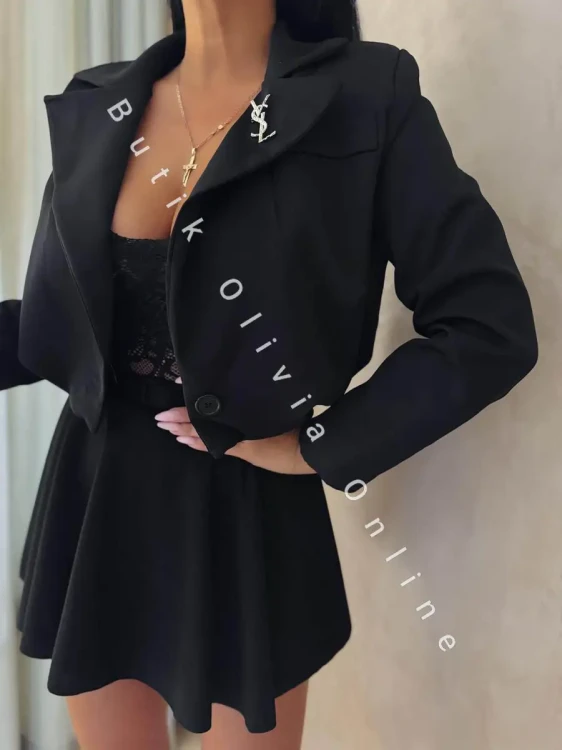 elegancka czarna krótka marynarka jak bomerka z broszką oraz poduszkami na ramionach