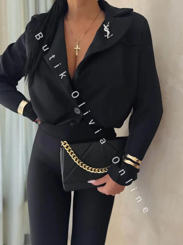 elegancka czarna krótka marynarka jak bomerka z broszką oraz poduszkami na ramionach